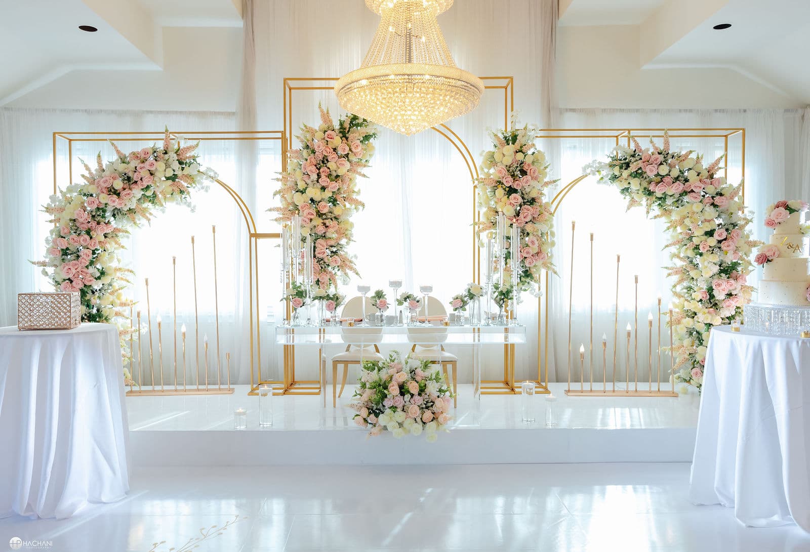 White wedding stage with pink flowers and gold stands