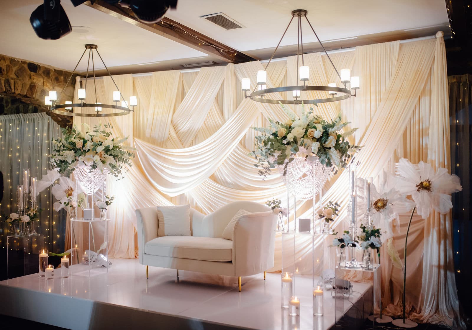 White draped wedding stage with floral arrangements